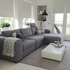 a living room with grey couches and white coffee table in front of large windows