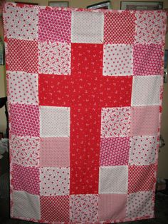 a red and white cross quilt hanging on a wall