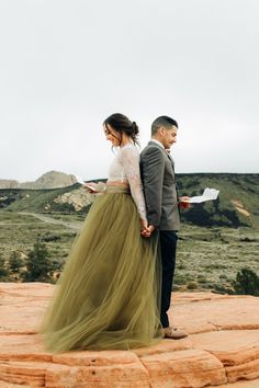 a man and woman standing on top of a rock