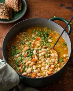 a pot filled with beans and vegetables on top of a wooden table