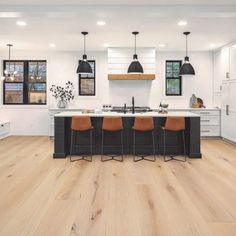 a kitchen with white walls and wooden flooring topped by two pendant lights hanging from the ceiling