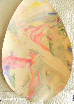 a white plate with multicolored paint on it sitting on top of a table