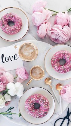 a table topped with donuts covered in pink sprinkles next to flowers