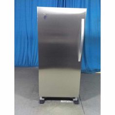 a silver refrigerator sitting on top of a metal stand