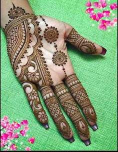 henna tattoo on the palm of someone's hand with flowers in the background