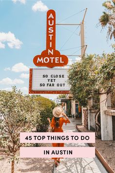 a woman in an orange dress and straw hat standing under a neon sign that reads, just in motel