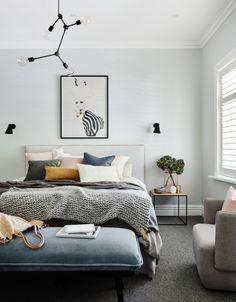 a bedroom with white walls and gray carpeted flooring, a bed in the center