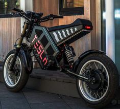 a black and red dirt bike parked next to a building