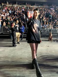 a woman holding a drink while standing in front of a crowd