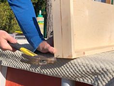 a person holding a pair of pliers on top of a piece of wooden furniture