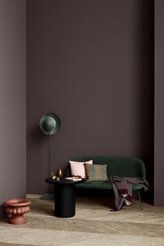 a green couch sitting next to a black table in a living room with brown walls