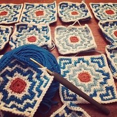 crocheted squares are arranged on a table with yarn