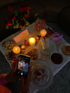 a person holding a cell phone in front of a table with food and candles on it