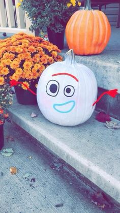 a pumpkin sitting on top of a cement step next to flowers and potted plants