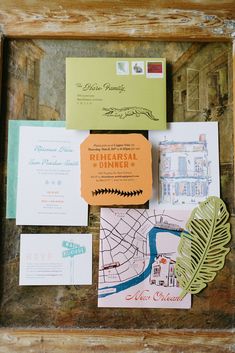 the wedding stationery is laid out in an old wooden frame with paper cutouts