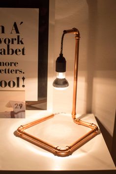 a desk lamp sitting on top of a white table next to a sign that says work babet more letters cool