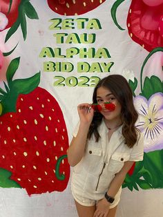 a woman standing in front of a sign with strawberries on it