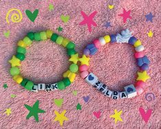 two bracelets with words on them sitting on a pink blanket