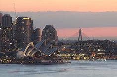 the sydney opera house is lit up at night in front of the cityscape