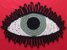 a crocheted eye is shown on a red surface with black and white trim