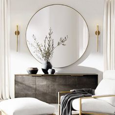 a living room with white furniture and a round mirror