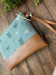 a leather pouch sitting on top of a wooden floor next to a plant and scissors