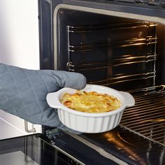 a person holding a casserole dish in front of an oven