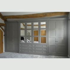 an empty room with gray cabinets and white sheets on the bed, in front of a wooden beam