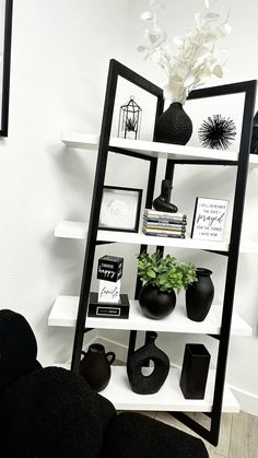 a black and white shelf with vases, bookshelves and pictures on it