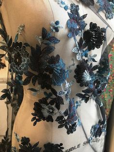 the back of a dress with blue and black flowers on it's chest,