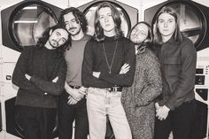 five people standing in front of a washing machine with their arms crossed and looking at the camera