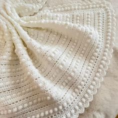 a white crocheted blanket laying on top of a bed