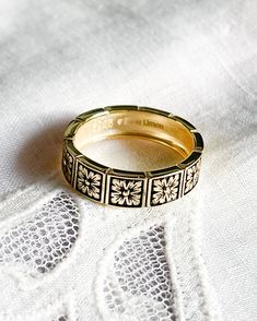 a gold wedding ring sitting on top of a white lace covered table cloth with the word love written across it