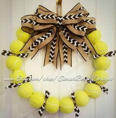 a tennis ball wreath hanging on a door with black and white stripes, brown bow