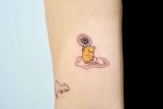 a woman's arm with a tattoo on it that has a cartoon character holding a flower