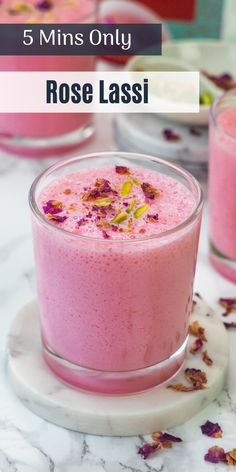 two glasses filled with pink smoothie sitting on top of a marble table next to other cups