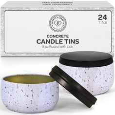 the candle tins are white and black with gold trimming on them, next to an empty box