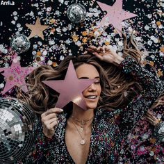 a woman holding a pink star surrounded by disco balls