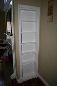 an empty white book shelf in the corner of a room