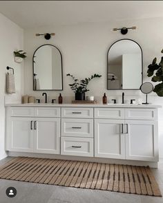 a bathroom with double sinks and two mirrors on the wall, along with a rug in front of it