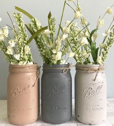 three painted mason jars with flowers in them