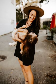 a woman holding a baby in her arms and wearing a hat on top of her head