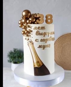 a white cake with gold decorations and a bottle of champagne on the top that says 85th birthday