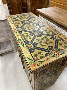 an ornately decorated wooden box sitting on top of a hard wood floor next to a bench