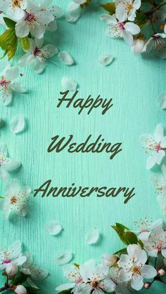 happy wedding anniversary card with flowers and leaves on blue wood planks in the background