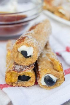 two pastries with blueberries are sitting on a napkin next to a glass bowl