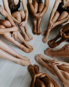 a group of women sitting in a circle with their bare feet on the floor,