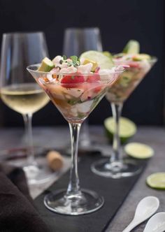 three glasses filled with different types of food on top of a black tray next to spoons