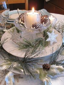 a candle is lit on top of a table with pine cones and evergreen branches around it