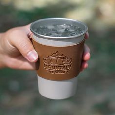 a person holding a cup with water in it and the words mountain coffee on it